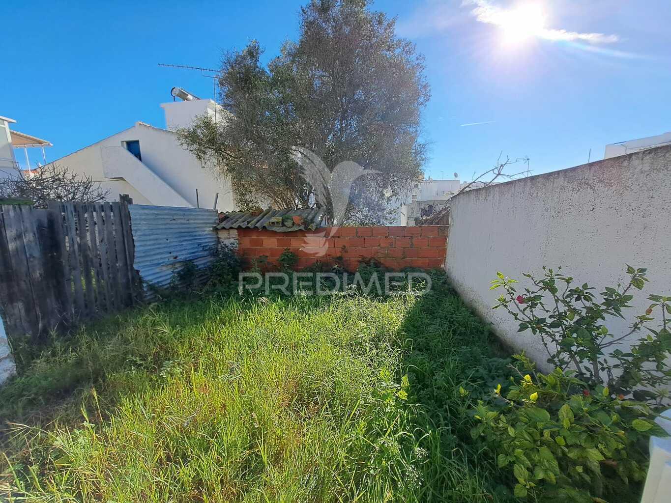 Terreno urbano com construção antiga no centro de quarteira